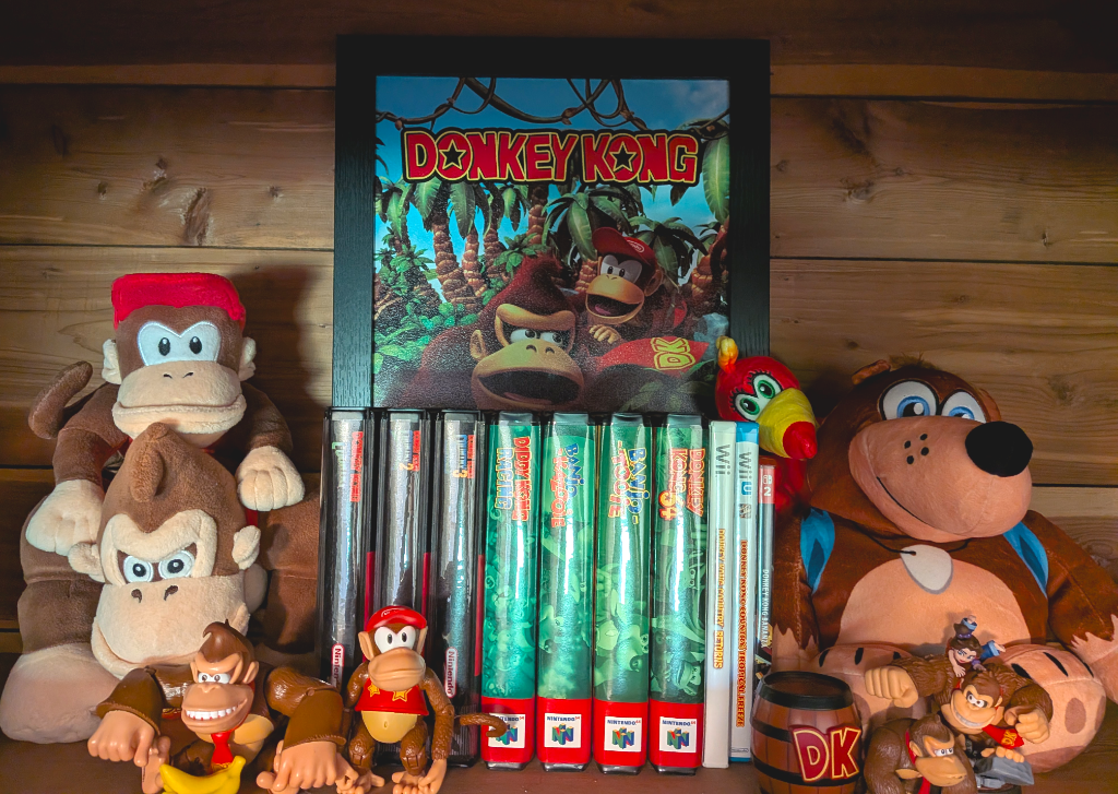 An assortment of Donkey Kong and Banjo-Kazooie games and figures, in front of a piece of framed Donkey Kong wall art