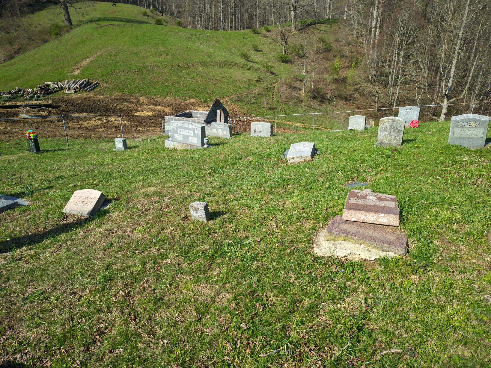 A graveyard scattered with broken headstones, debris, and delapidated outbuildings