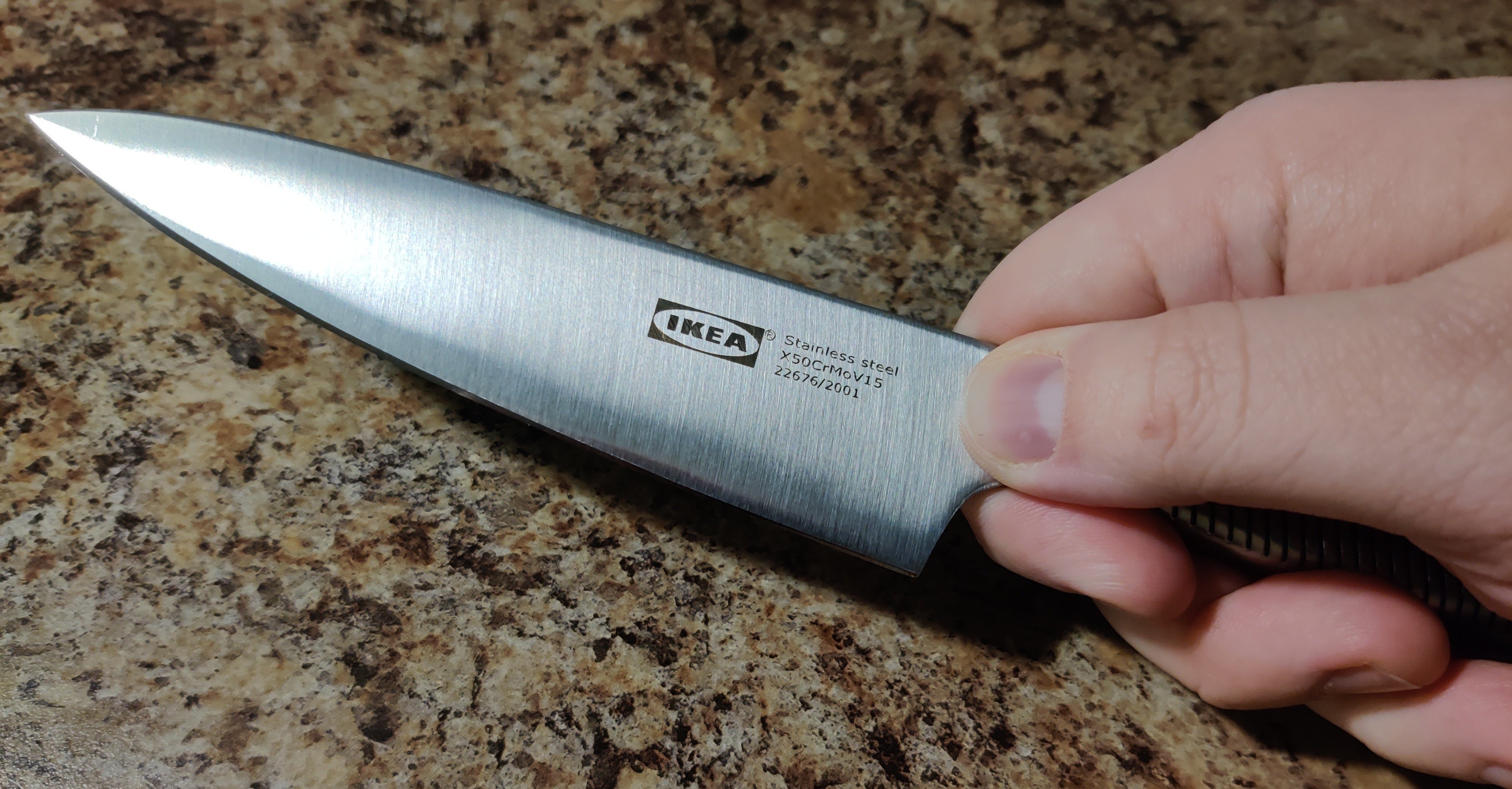 A small, stainless steel IKEA utility knife being held between thumb and forefinger