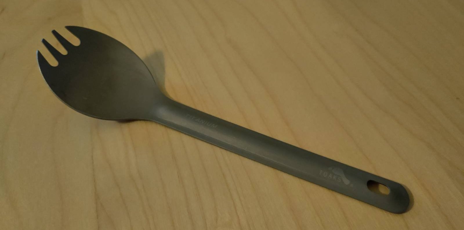 A titanium spork sitting on a wooden desk